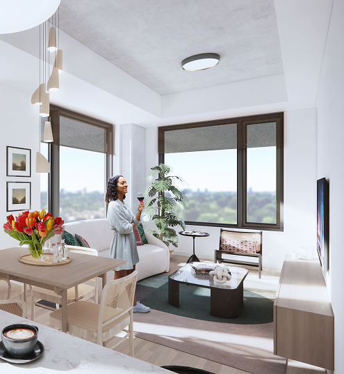 A woman stands in The Parkstone Party Room, holding a coffee cup in a cozy living room setting.