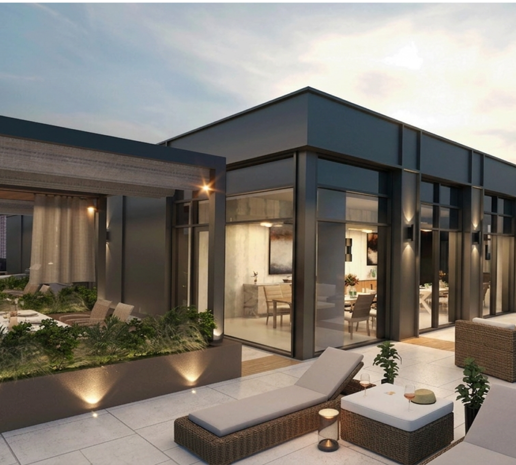Rooftop terrace outside an apartment lounge with chairs and plants.