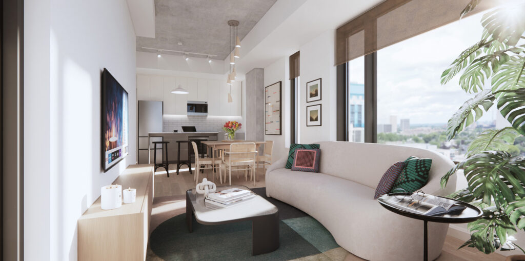 Bright apartment living room with a couch, TV, kitchen, large windows, and plant off to the side.